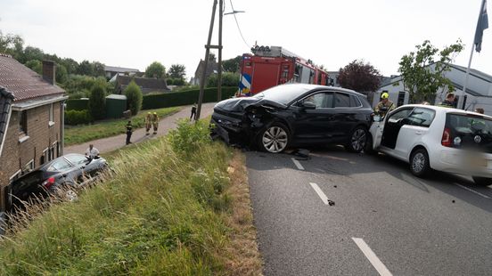 Ongeluk tussen drie auto's, één rolt van dijk af tegen huis aan