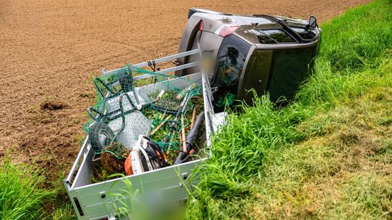 Auto met aanhangwagen vol groenafval belandt in sloot