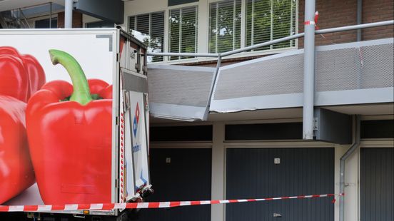 Vrachtwagen ramt galerij van flat
